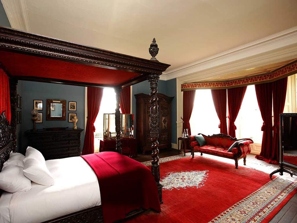A deep red traditional rug scaled for a formal bedroom with classic furnishings.