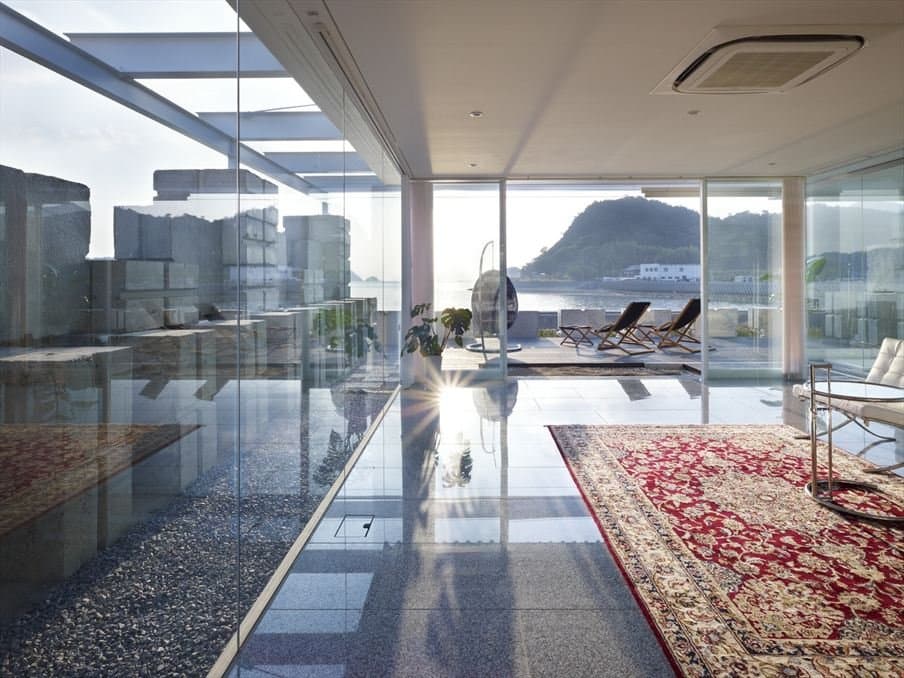 A traditional patterned rug grounding a contemporary glass-walled living space.