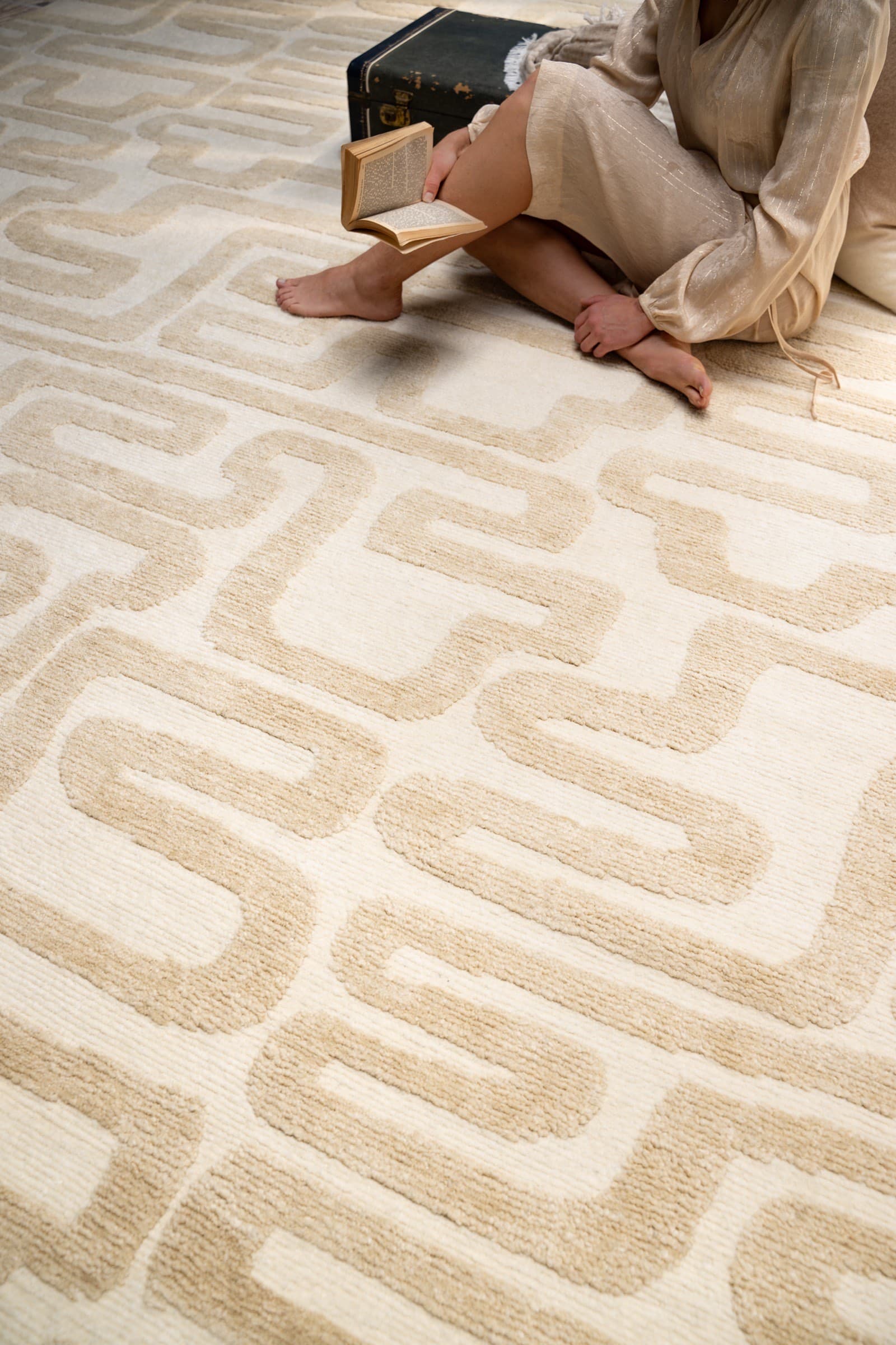 Contemporary geometric rug with a reader seated on it