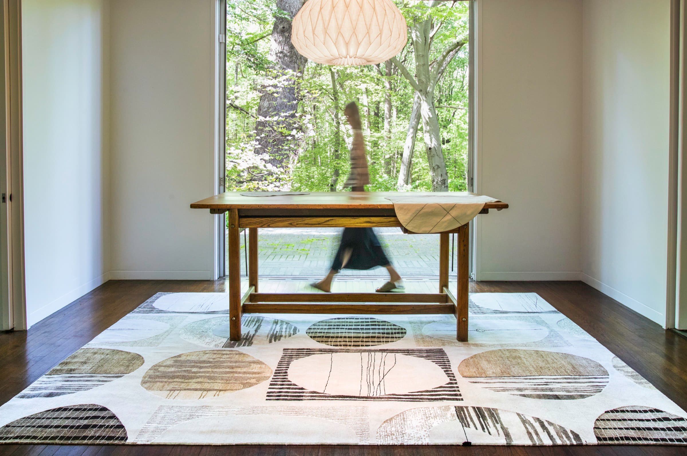 Contemporary geometric rug in a sunlit dining room overlooking the trees